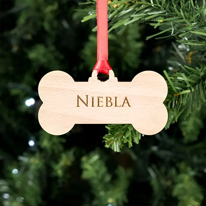 Adorno navideño personalizado en forma de hueso de madera con el nombre "Niebla", ideal para decorar el árbol de Navidad y celebrar las fiestas junto a tu mascota.