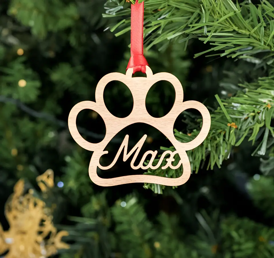 Pieza de madera para decorar arbol para navidad con forma de huella de perrito y un nombre, en este caso Max.