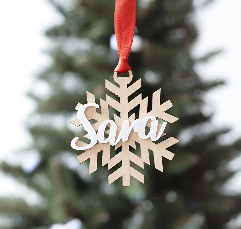 Copo de nieve de madera blanca con el nombre Sara escrito en color natural, ideal para decorar el árbol de Navidad.
