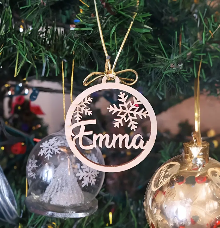 Adorno navideño de madera personalizado en forma de círculo con el nombre "Emma" y copos de nieve.