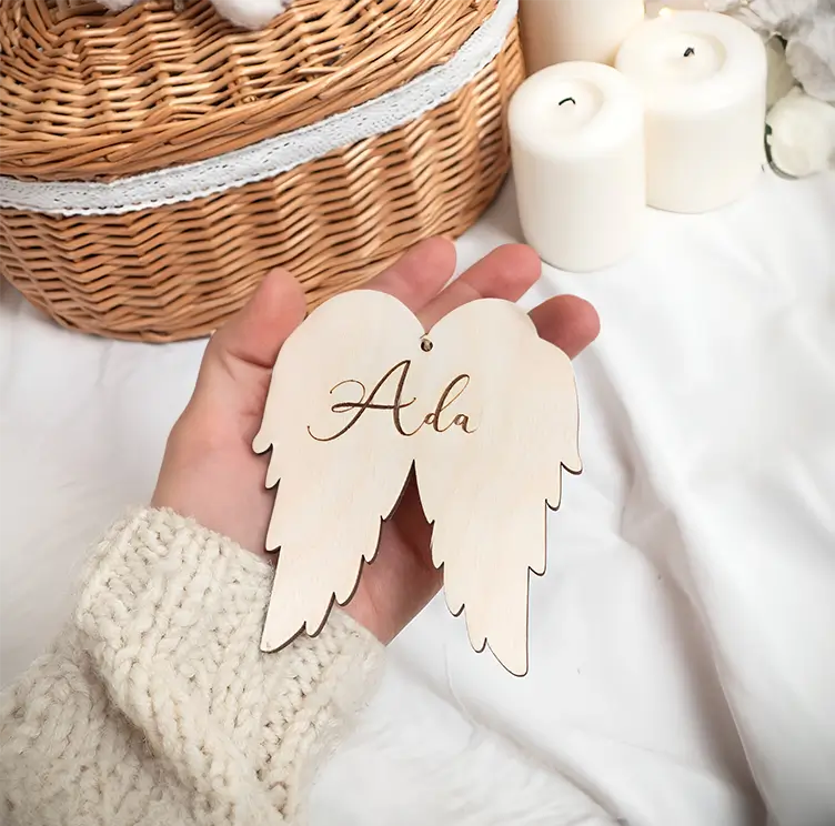 Originales adornos navideños de madera con diseño de alas de ángel y nombres personalizados.