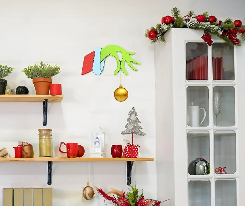 Figura decorativa navideña en MDF representando la mano del Grinch, con detalles nítidos y contrastes de color. Fondo de parquet en tonos claros.