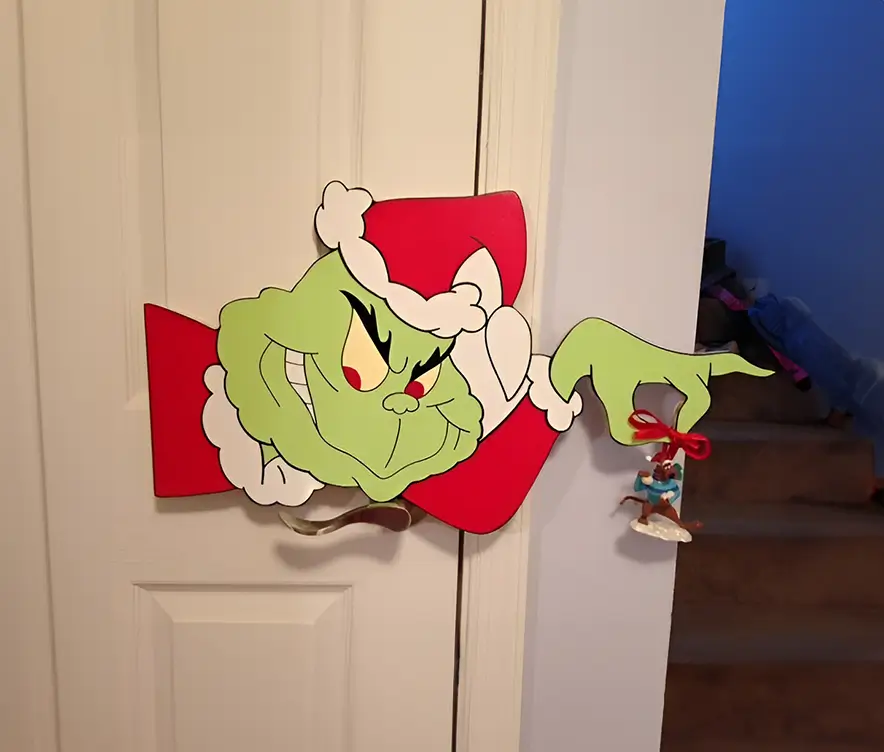 Diseño en relieve del Grinch en pose icónica, con detalles pintados a mano y acabados de alta calidad. Accesorio único para decoraciones navideñas modernas.