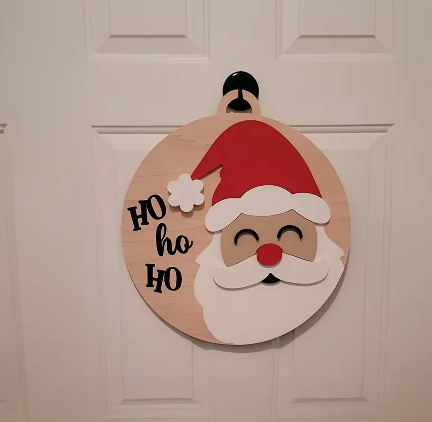 Figura decorativa de Santa Claus: diseño circular de madera con el clásico "Ho Ho Ho". Ideal para regalar o para uso personal durante las fiestas navideñas.